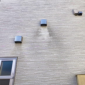 グレーの外壁で排気口近くに黒ずんだ汚れが堆積している様子