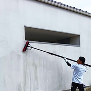 黒カビが垂れて黒ずんだ白い家の外壁